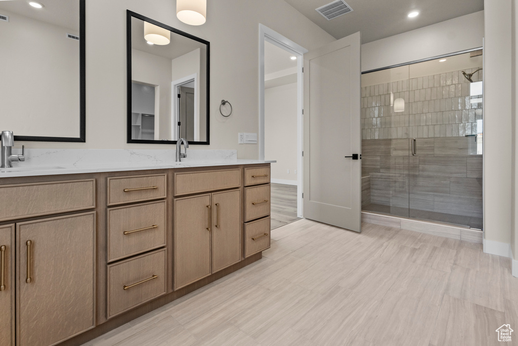 Bathroom featuring double vanity, a shower stall, and recessed lighting