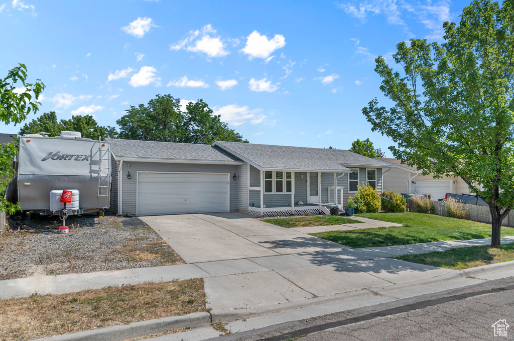 Single story home with an attached garage, concrete driveway, covered porch, and roof with shingles