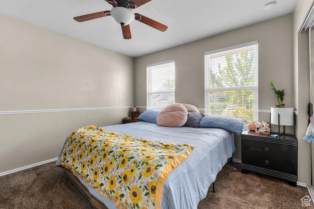 Carpeted bedroom featuring a ceiling fan and baseboards