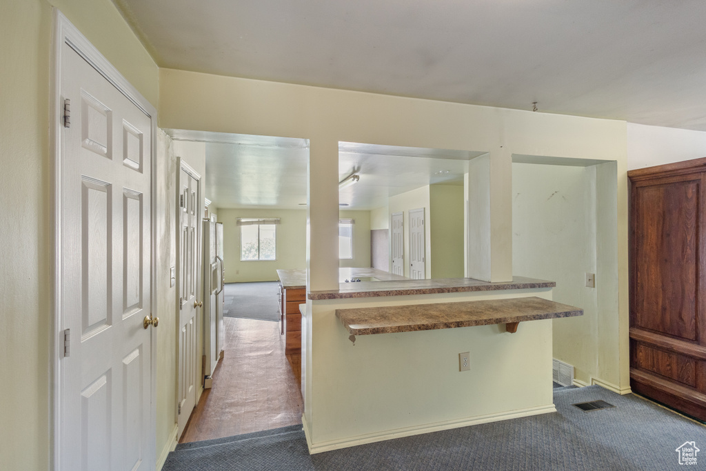 Kitchen featuring dark colored carpet and a breakfast bar area