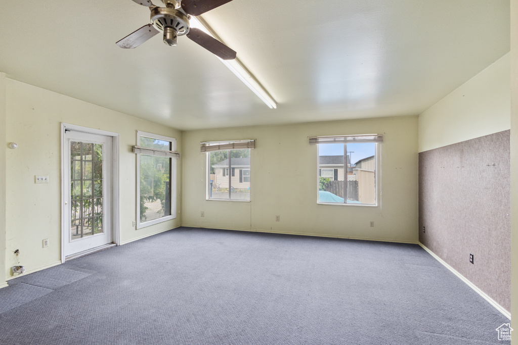 Carpeted empty room with a ceiling fan and baseboards