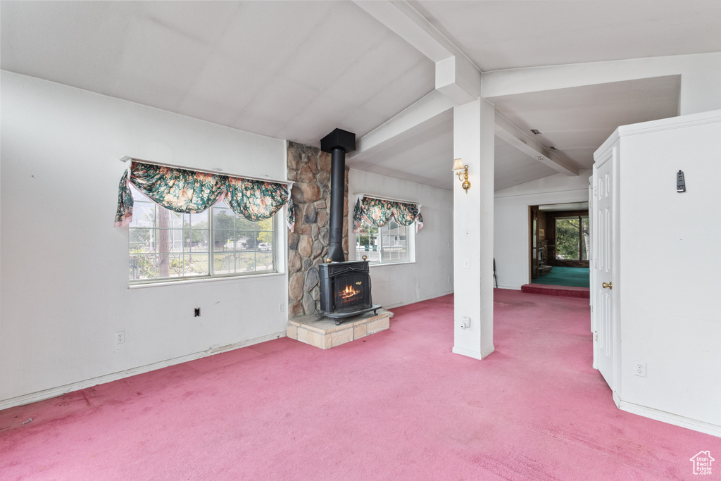 Unfurnished living room with carpet flooring, a wood stove, and healthy amount of natural light
