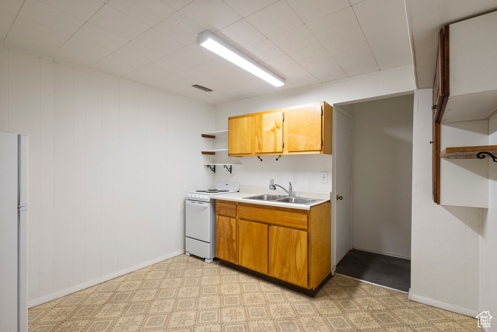 Kitchen featuring white appliances, open shelves, light countertops, brown cabinetry, and light floors