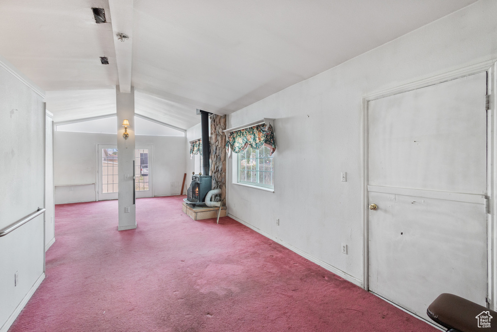 Unfurnished living room with a wood stove, plenty of natural light, and carpet