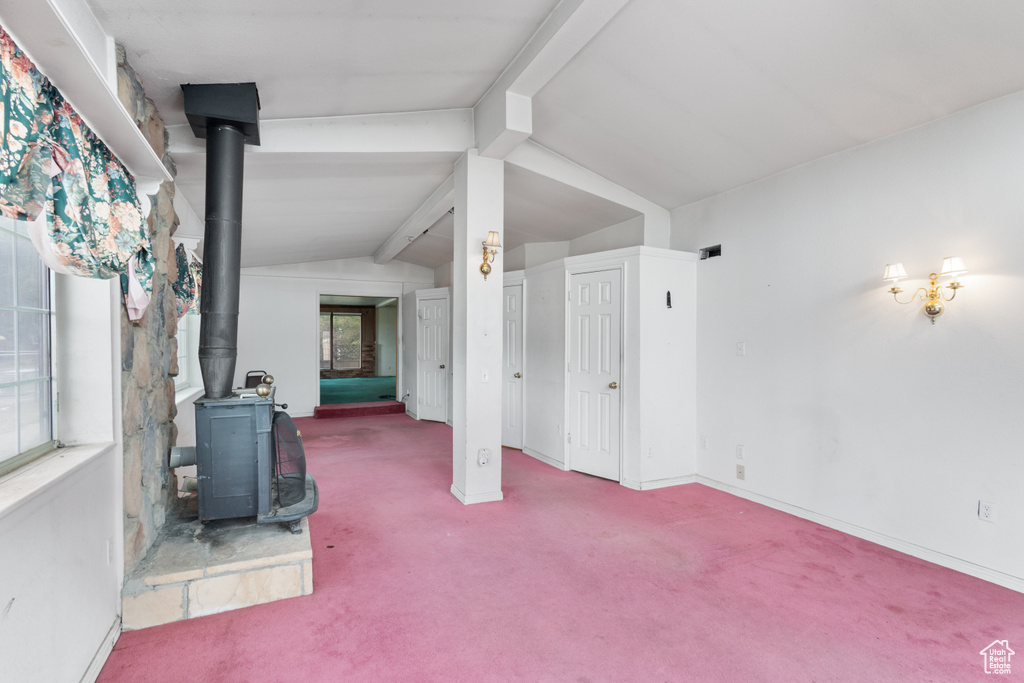 Unfurnished living room with a wood stove and carpet flooring