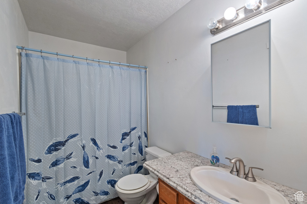 Bathroom with vanity, a shower with shower curtain, and a textured ceiling