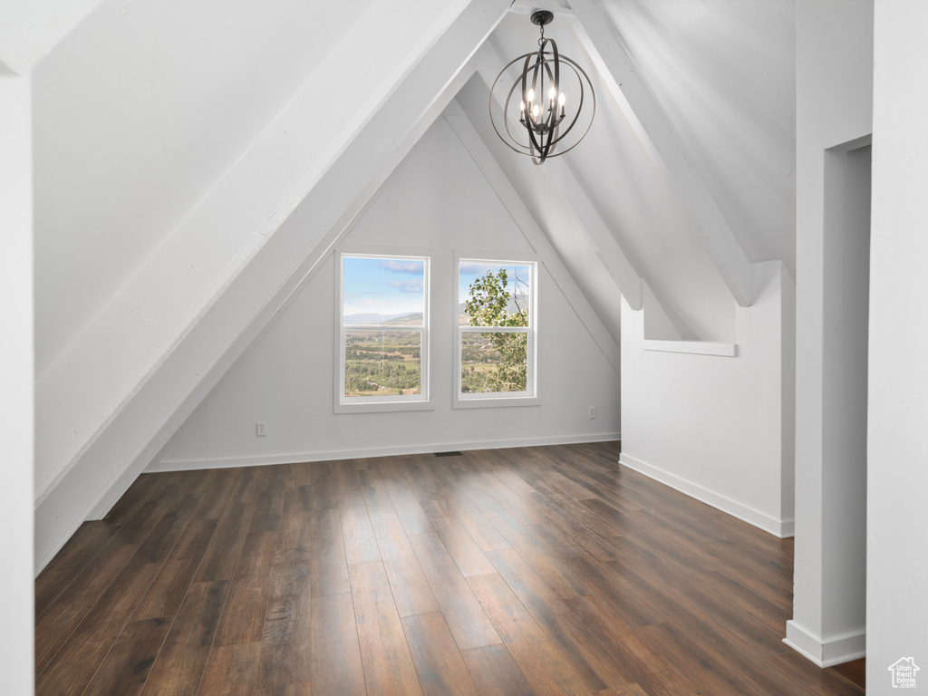 Bonus room featuring a chandelier, dark wood-style flooring, and vaulted ceiling