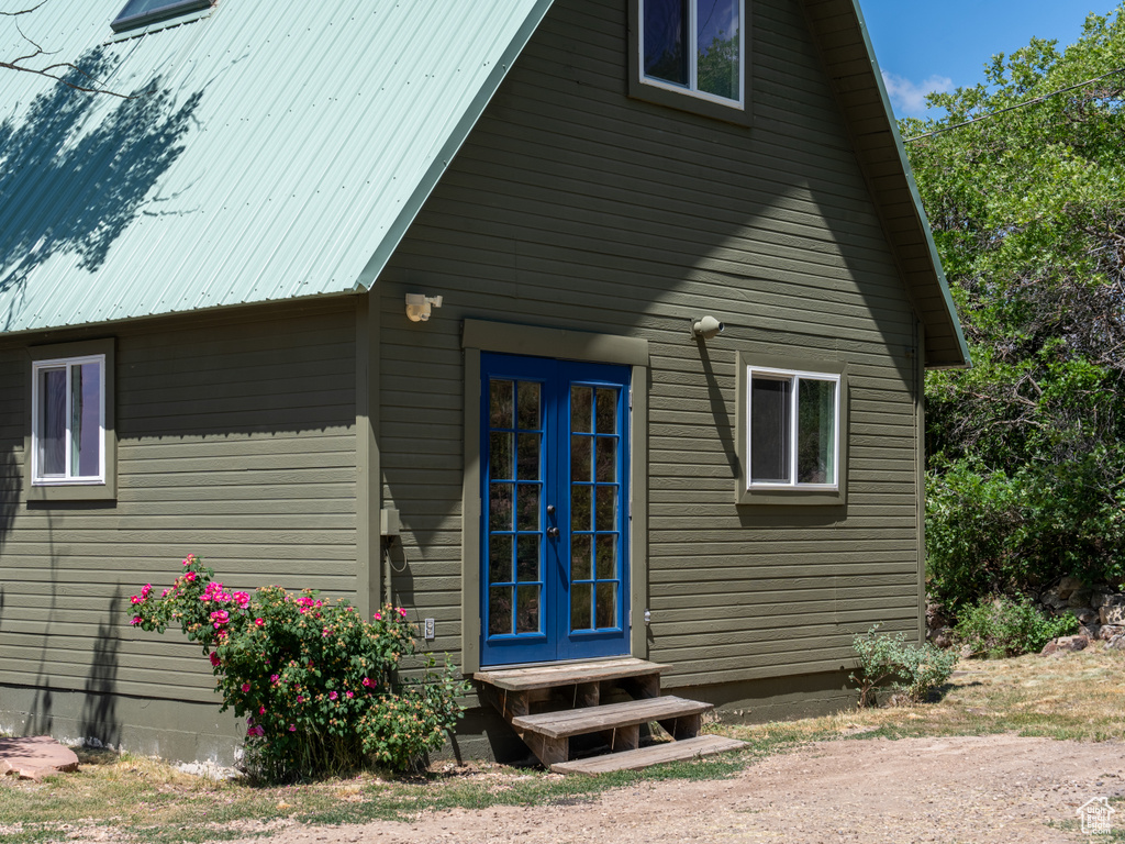 View of property exterior featuring french doors, entry steps, and a metal roof