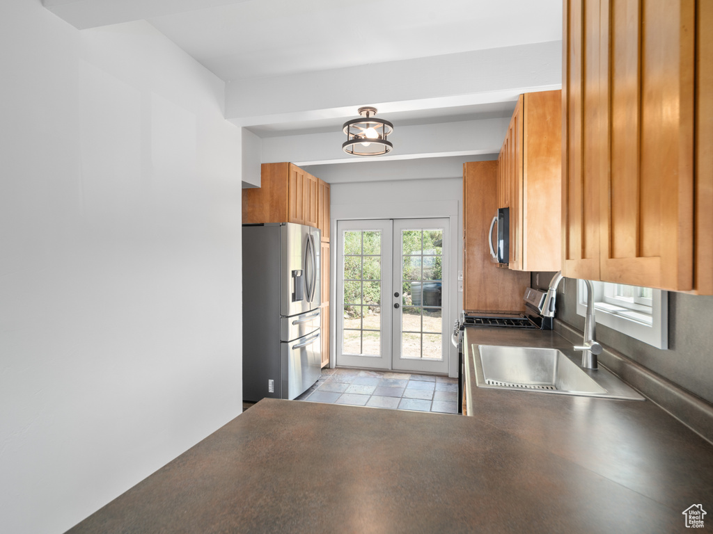 Kitchen featuring appliances with stainless steel finishes, french doors, dark countertops, and brown cabinets