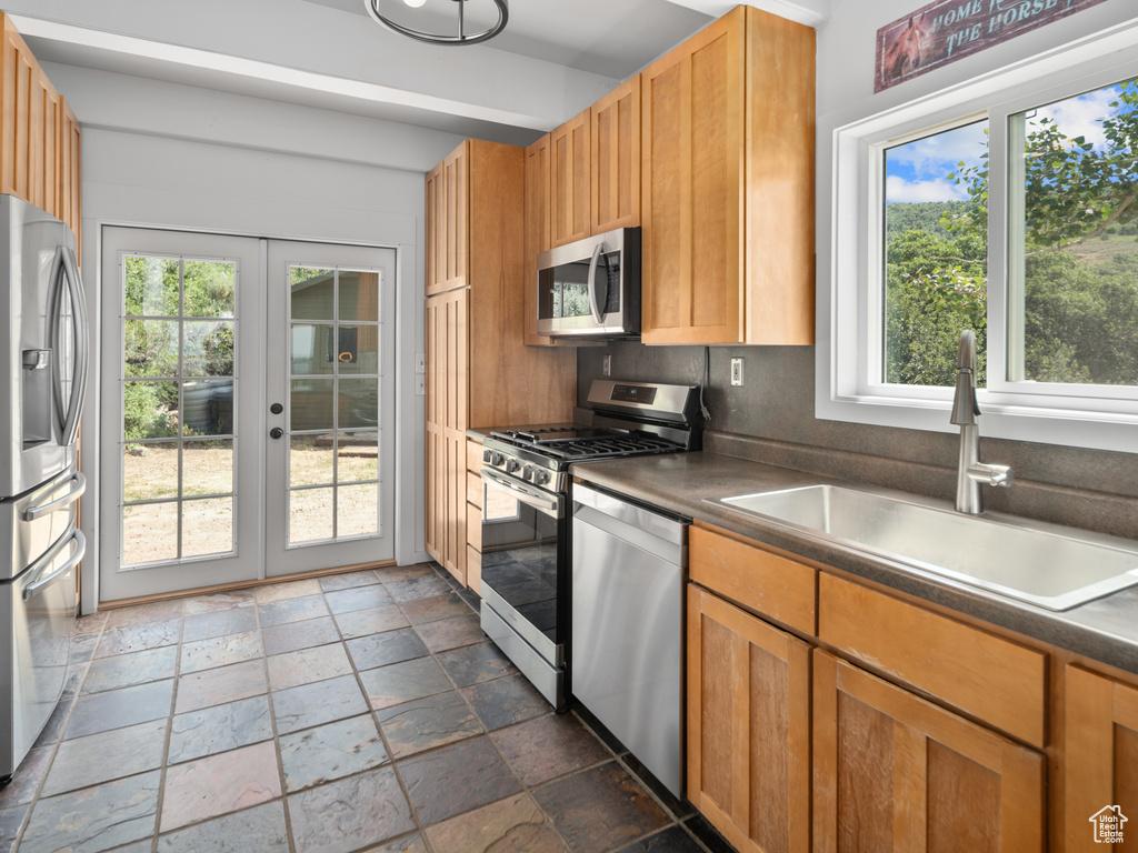 Kitchen featuring stainless steel appliances, stone tile flooring, plenty of natural light, and french doors