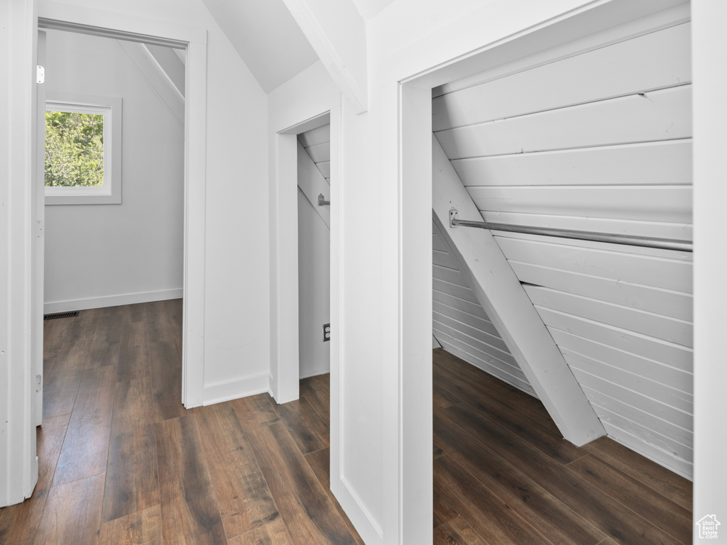 Hallway with dark wood finished floors and vaulted ceiling