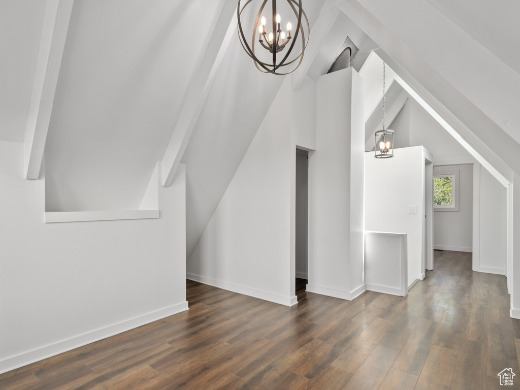 Bonus room featuring a chandelier, dark wood-style floors, and vaulted ceiling