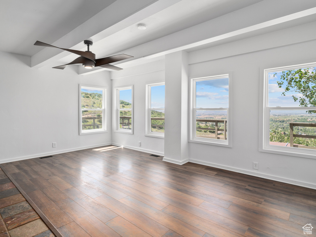 Empty room with dark wood finished floors and a ceiling fan