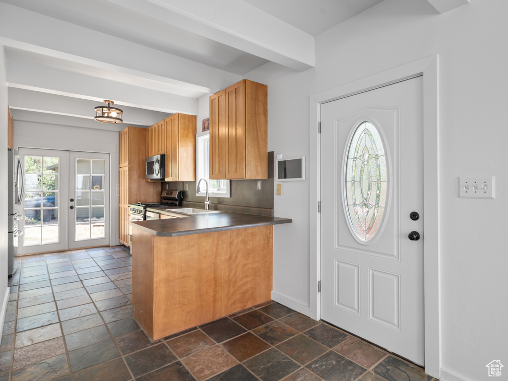 Kitchen featuring stainless steel appliances, stone tile floors, dark countertops, and a peninsula
