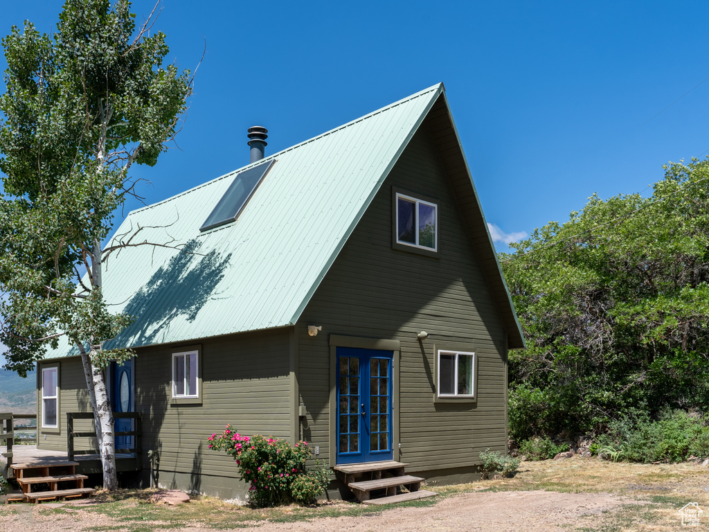 Rear view of property featuring french doors, a deck, and a metal roof