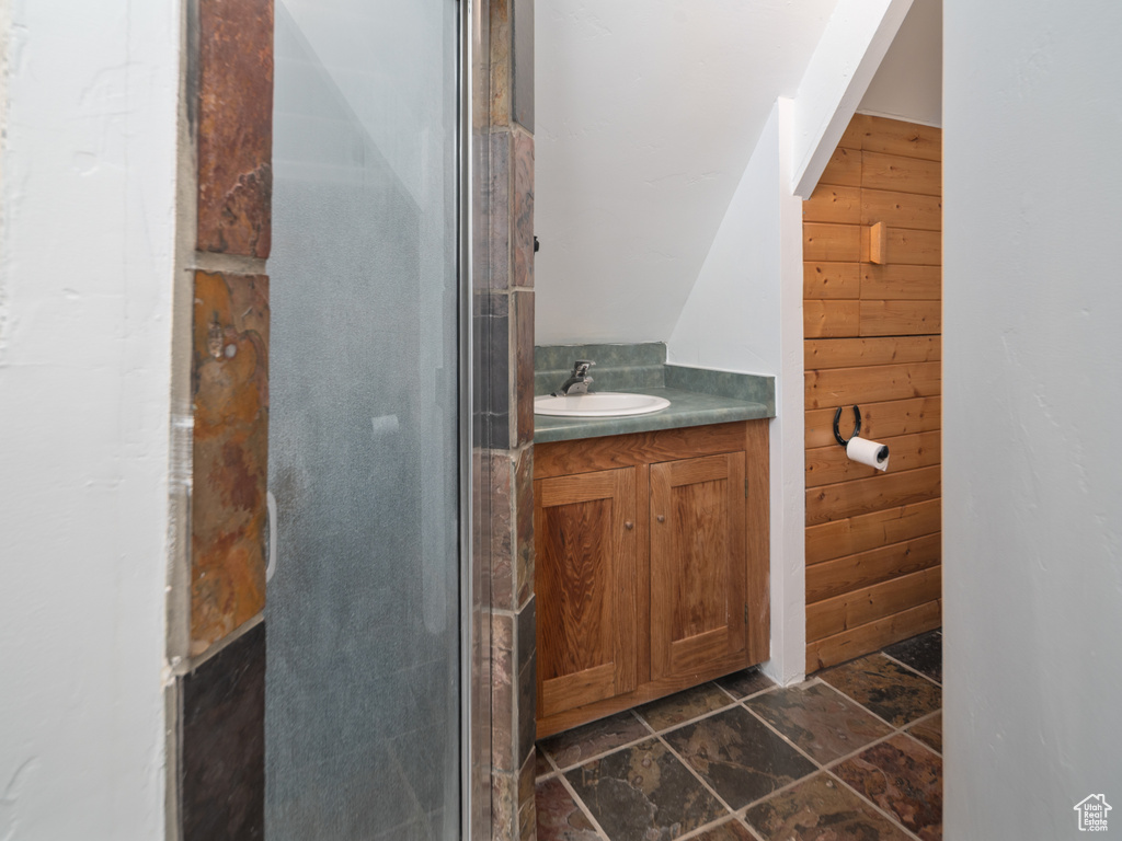Bathroom with vanity, wooden walls, and stone finish floors