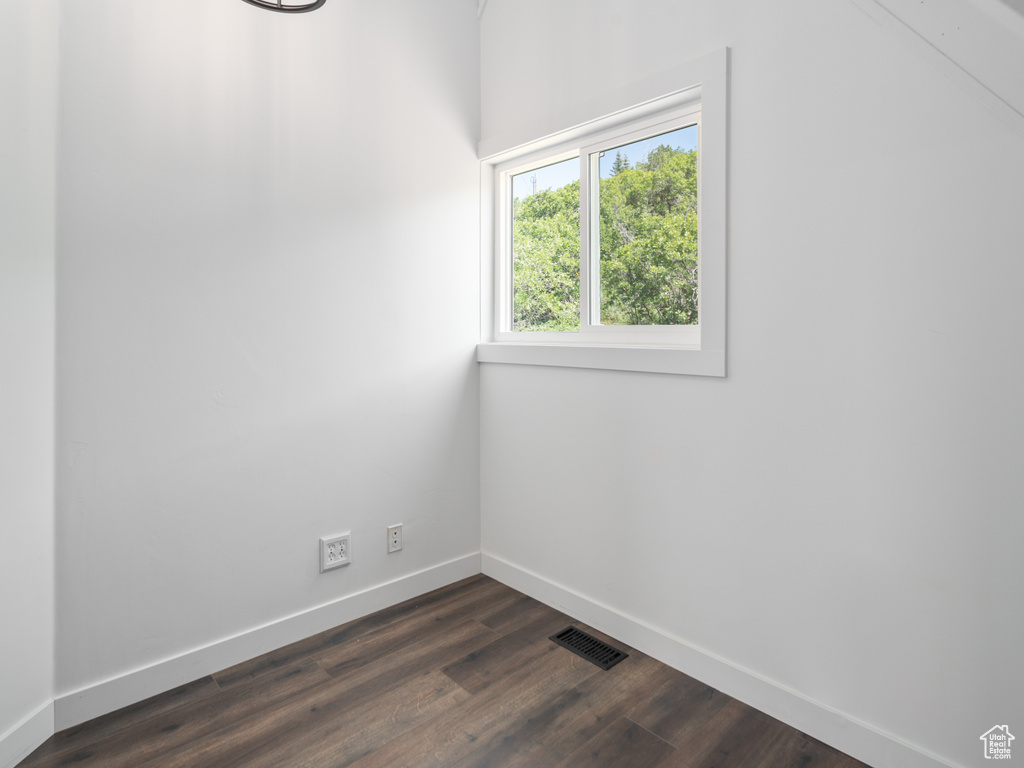 Unfurnished room with baseboards and dark wood-style flooring