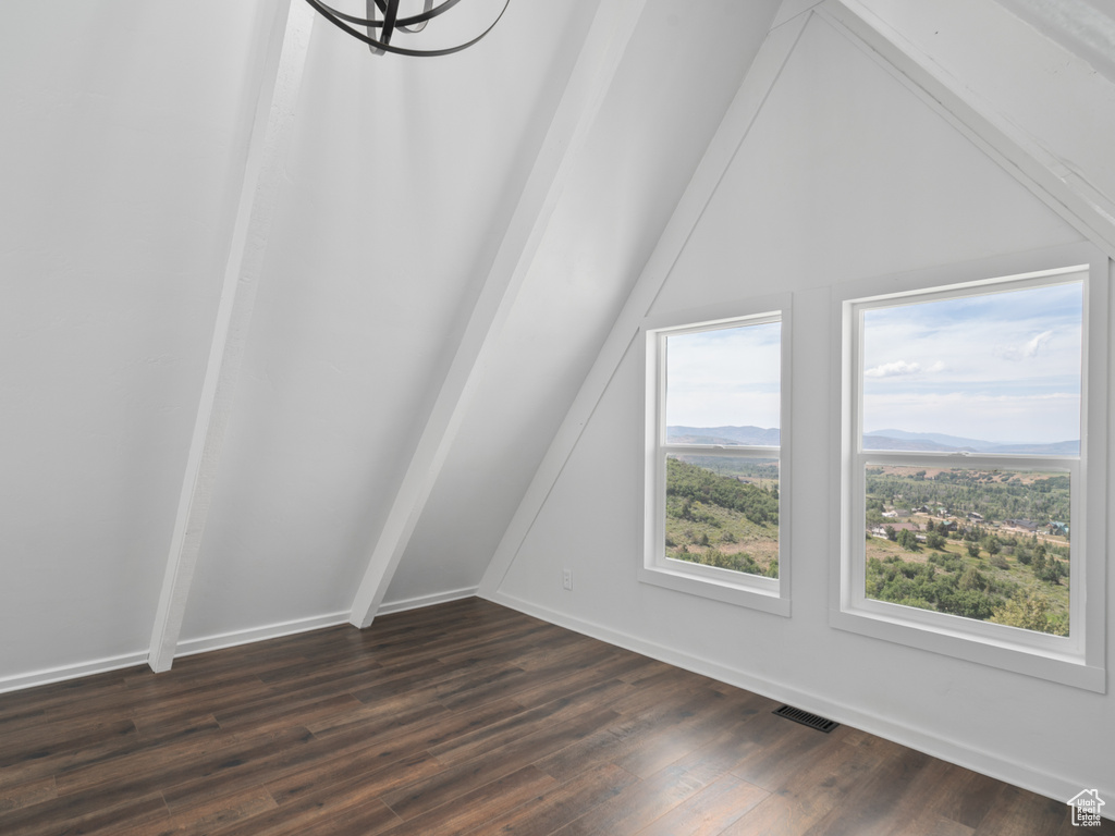 Additional living space featuring vaulted ceiling, dark wood-type flooring, a chandelier, and a mountain view