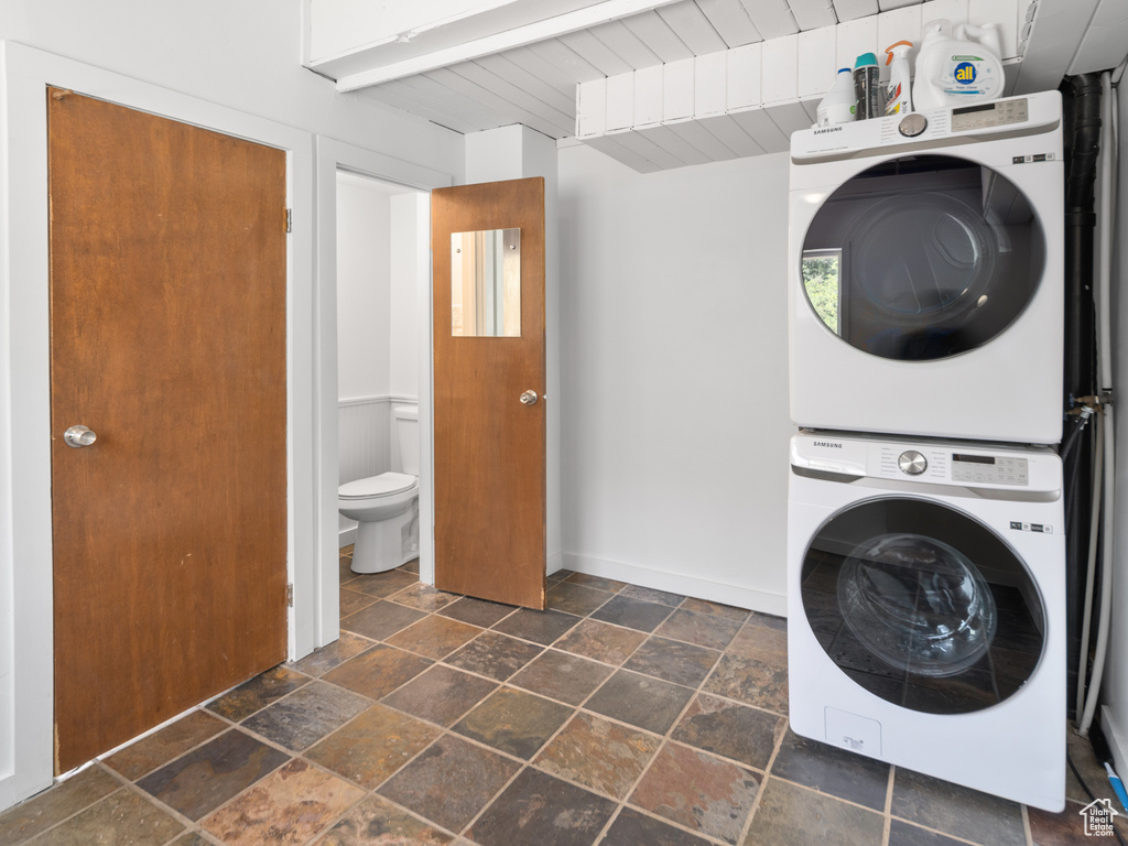 Laundry area featuring estacked washer and dryer, stone tile flooring, and wooden ceiling