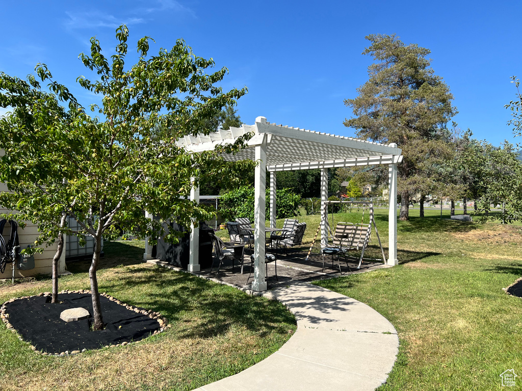 View of green lawn with a pergola and a patio area