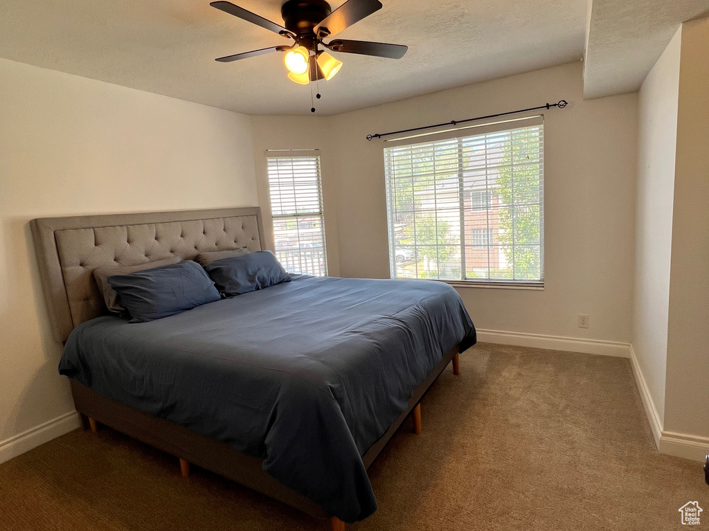 Carpeted bedroom featuring a textured ceiling and ceiling fan
