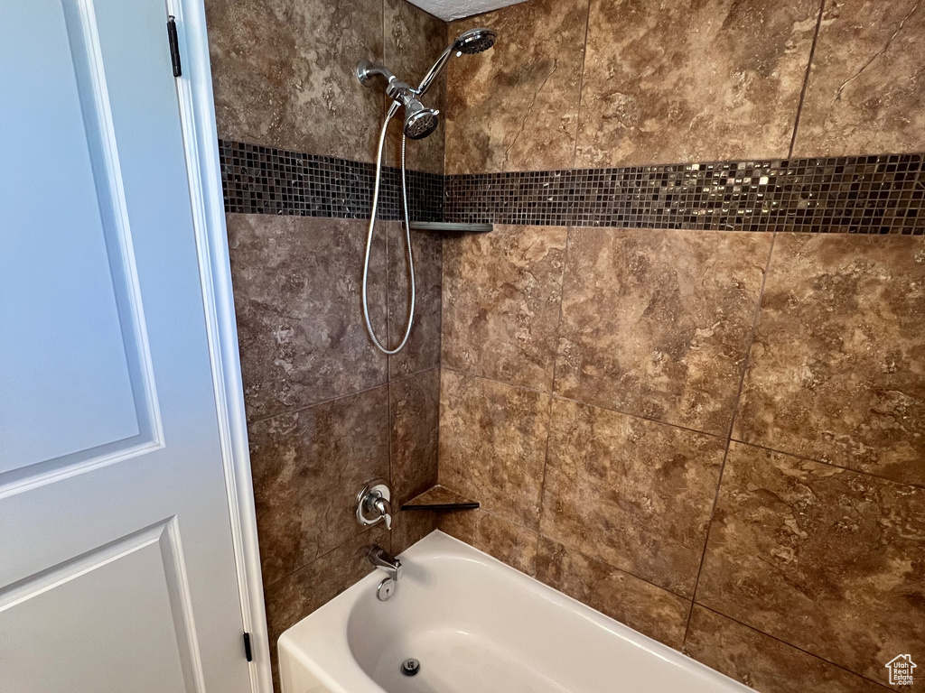 Bathroom featuring a textured ceiling and bathing tub / shower combination