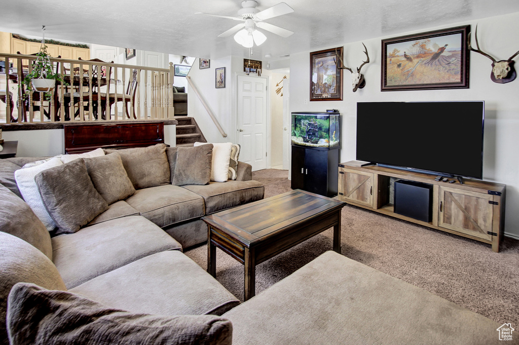 Living area with carpet floors, stairway, and a ceiling fan