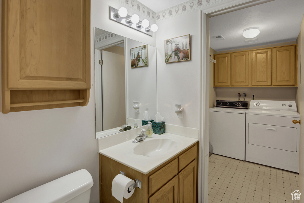 Half bathroom with washing machine and clothes dryer and vanity