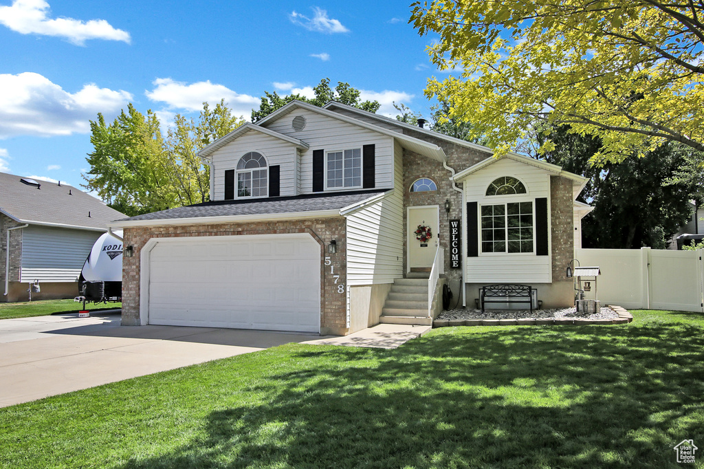 View of front of property with brick siding, an attached garage, and driveway