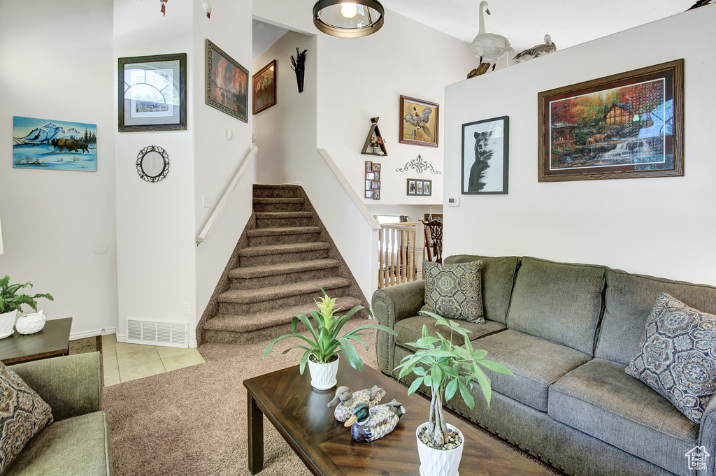 Carpeted living room featuring stairway and tile patterned flooring