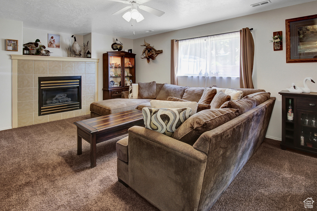 Carpeted living room featuring ceiling fan and a fireplace