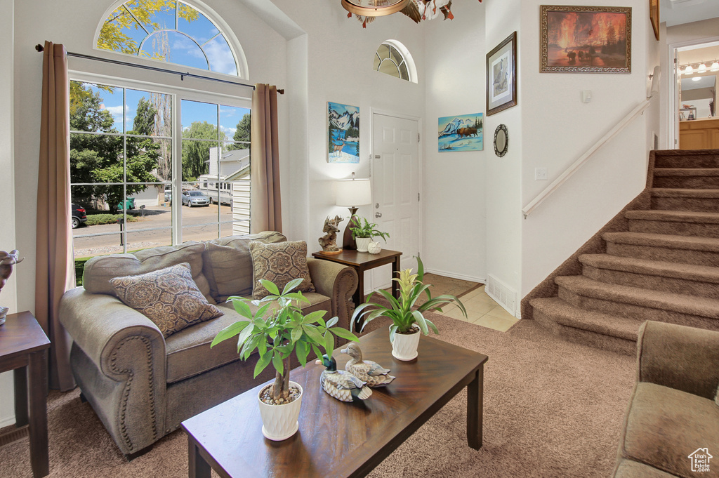 Living room featuring light carpet, stairs, and a high ceiling