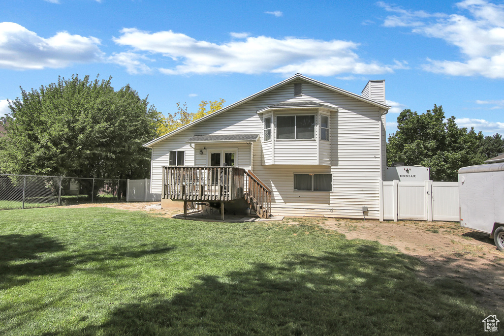Rear view of property featuring a gate, a wooden deck, french doors, a fenced backyard, and a chimney