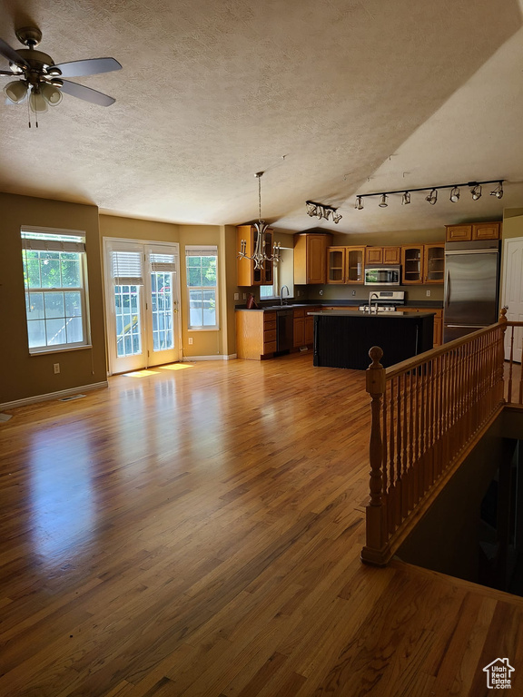 Living area featuring a textured ceiling, healthy amount of natural light, wood finished floors, a chandelier, and track lighting