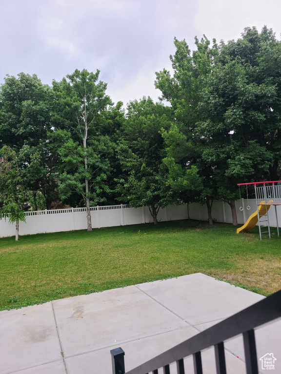 Fenced backyard featuring a playground and a patio