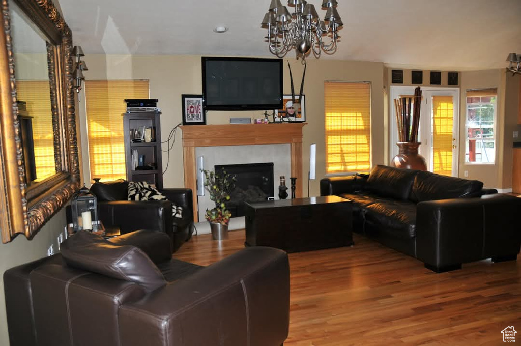 Living room with a chandelier, wood finished floors, and a fireplace