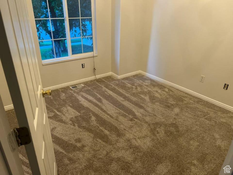 Spare room with dark colored carpet and baseboards