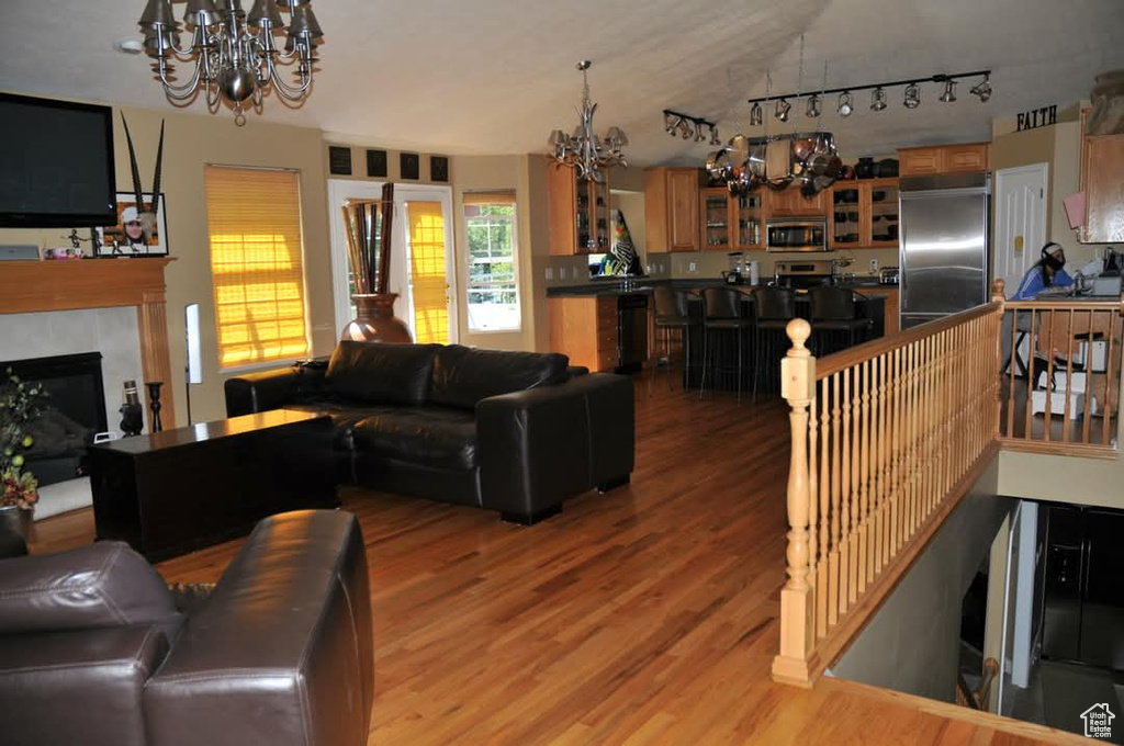 Living area featuring a chandelier, light wood finished floors, a fireplace, vaulted ceiling, and track lighting