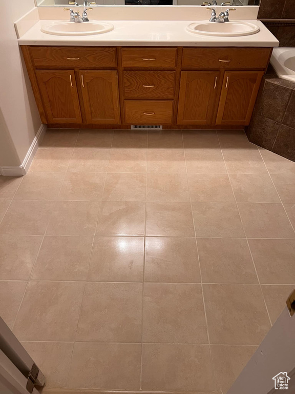 Full bathroom with double vanity, tile patterned floors, and a tub to relax in