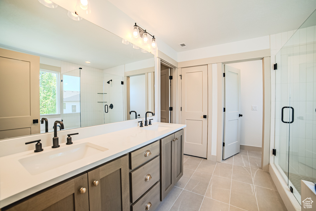 Bathroom with double vanity, a shower stall, and tile patterned floors