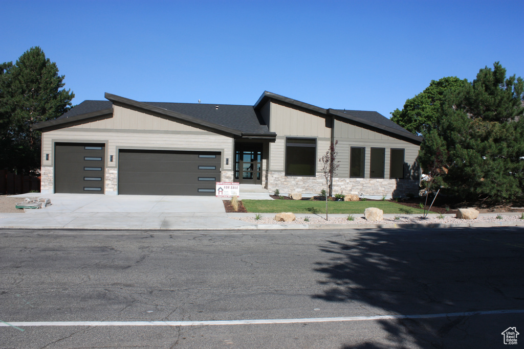 View of front of property featuring a garage, stone siding, and concrete driveway