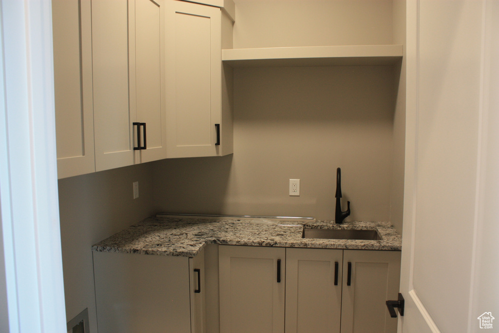 Kitchen featuring a sink and light stone counters