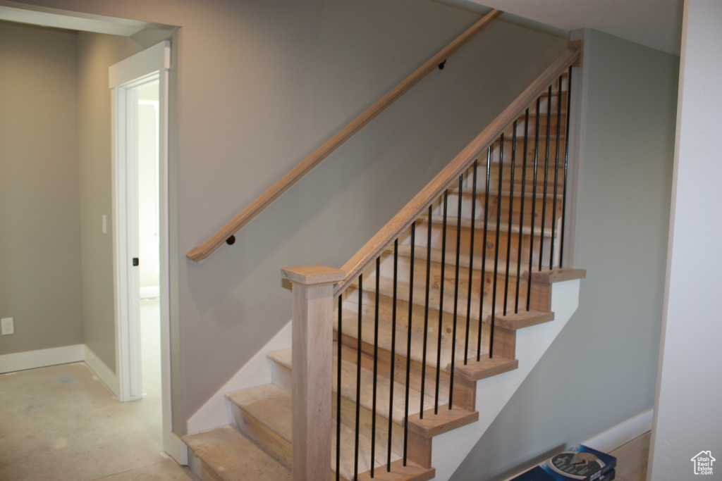 Stairway with baseboards and concrete floors