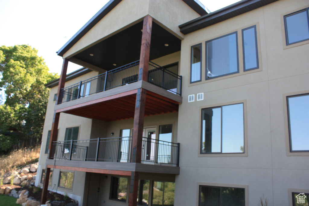 Back of property featuring a balcony and stucco siding