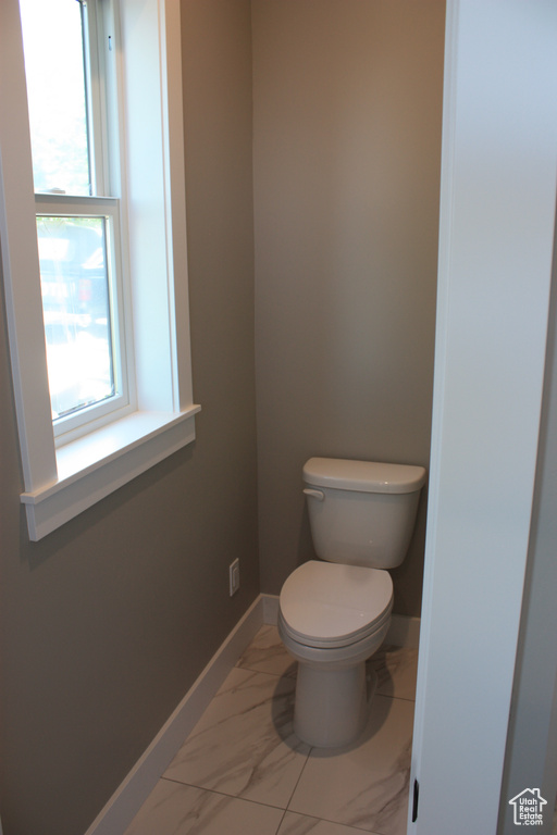 Bathroom featuring toilet and marble look tiles