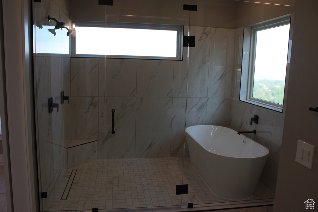 Full bath featuring plenty of natural light, a marble finish shower, and a freestanding bath