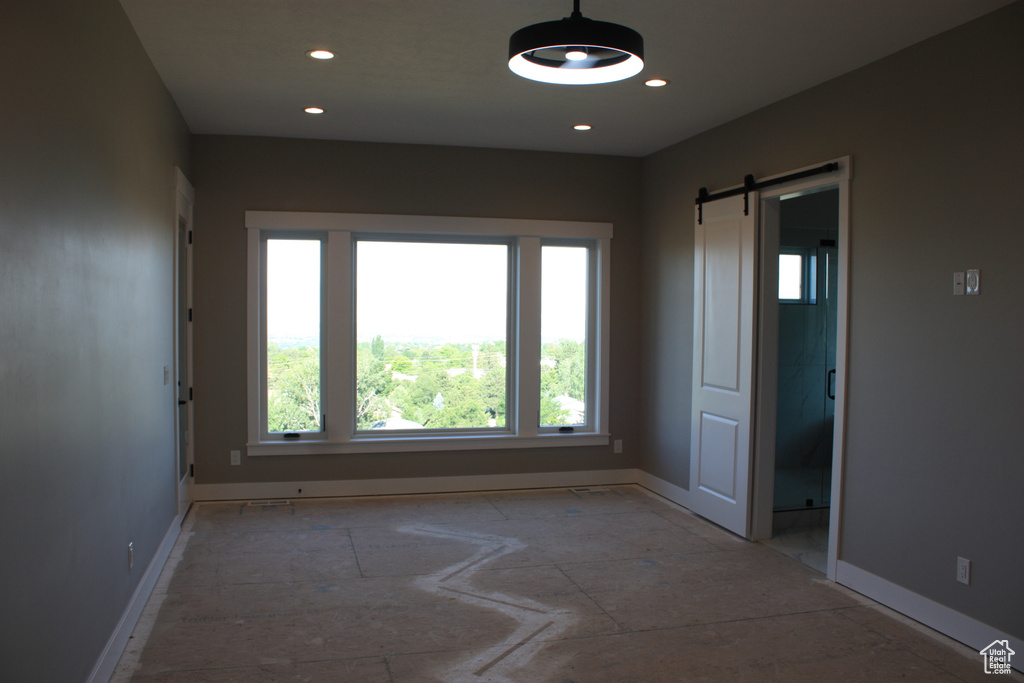 Empty room featuring a barn door and recessed lighting