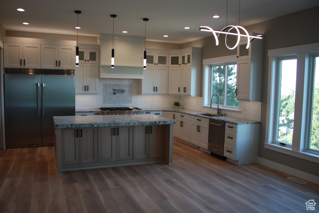 Kitchen with stainless steel appliances, dark wood-style floors, a kitchen island, white cabinets, and glass insert cabinets
