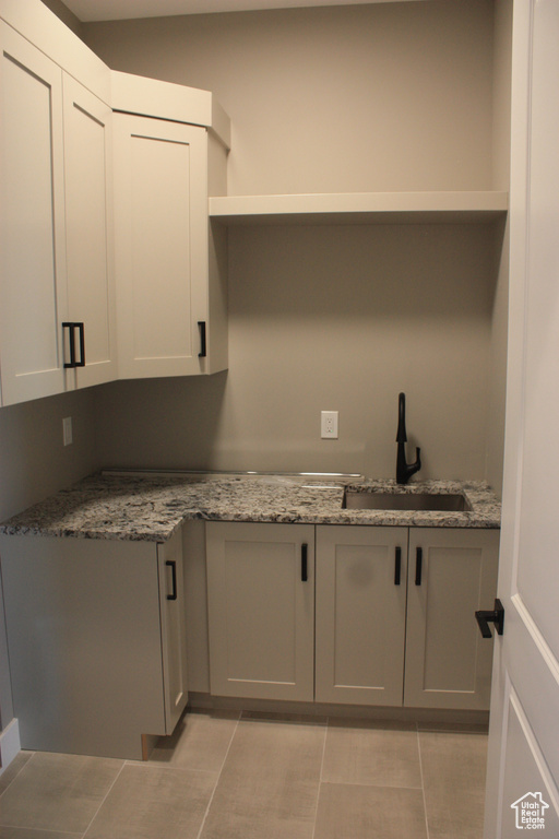 Kitchen with light tile patterned floors, gray cabinets, and light stone counters