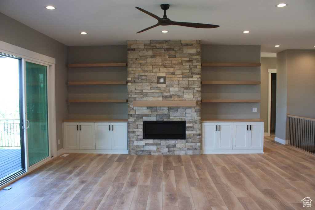 Unfurnished living room featuring a ceiling fan, plenty of natural light, light wood finished floors, a stone fireplace, and recessed lighting